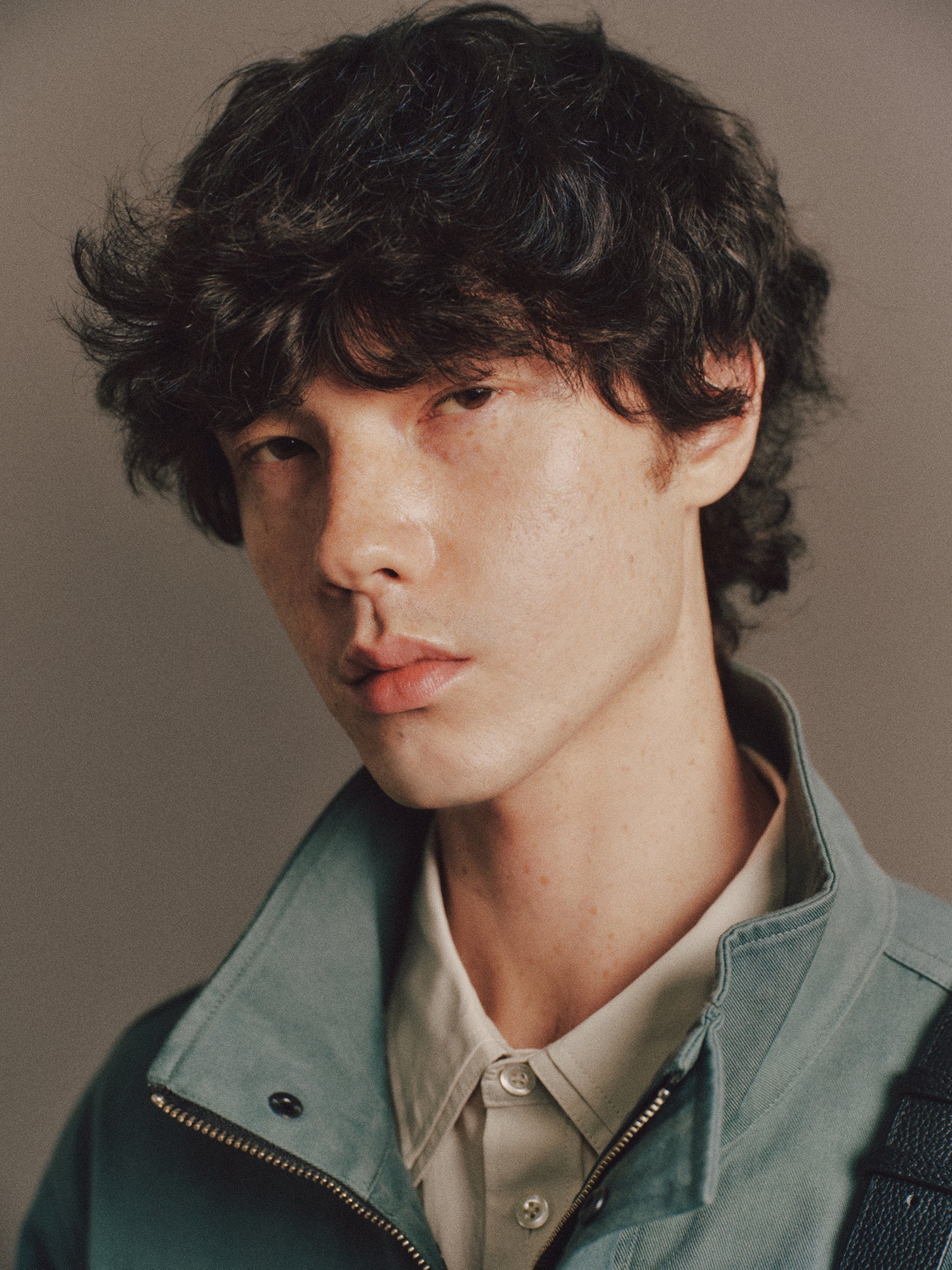 Émile wears Burt Shirt In Light Green, Archie Jacket In Green, Satie Jean In Washed Black, Cow Leather Aura Bag In Black