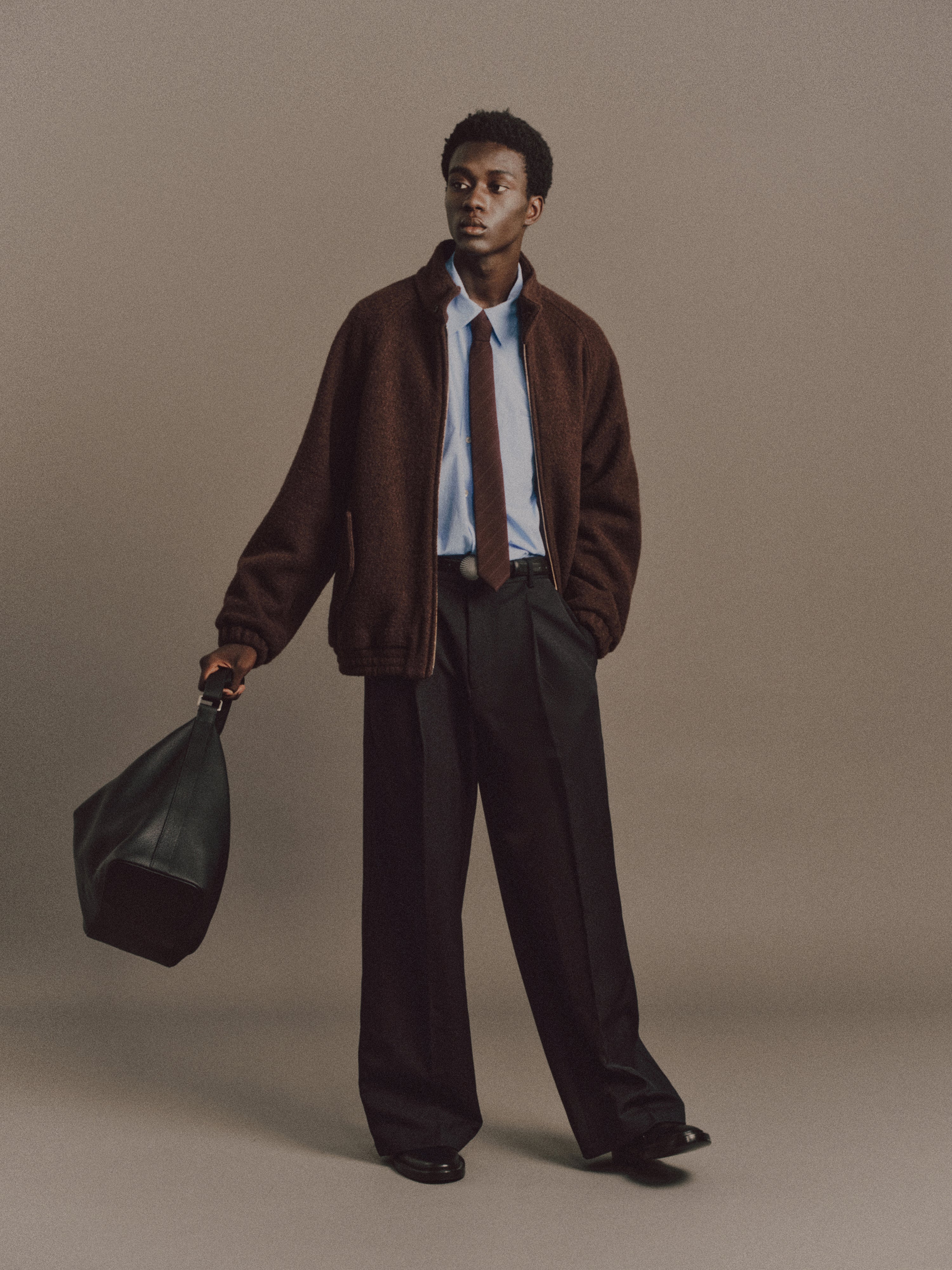 Muhamed wears Haley Shirt in Light Blue, Luka Pant in Black, Charlotte Tie In Wine Red Stripe, Shell Belt In Vintage Silver, Cow Leather Aura Bag In Black